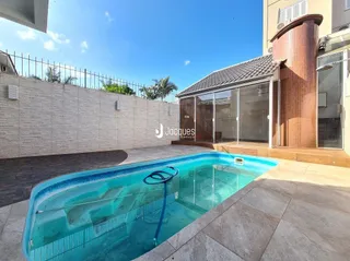Piscina externa com deck e parede de alvenaria.