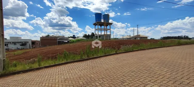 Vista da propriedade com terreno e estrutura no fundo.