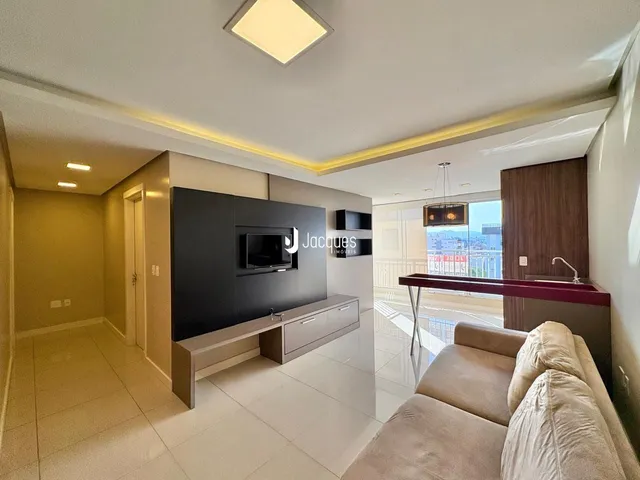 Sala de estar moderna com sofá e parede de TV em um apartamento.