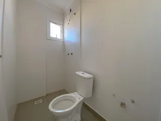 Foto de um banheiro interno com piso claro e vaso sanitário branco.