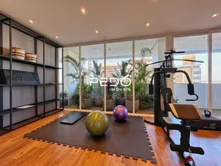 Interior de uma sala com piso de madeira e equipamentos de ginástica.