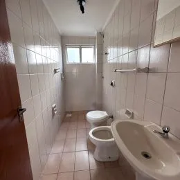 Corredor interno com paredes brancas e piso de cerâmica.