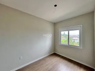Ambiente interno de uma sala com piso de madeira e janela.