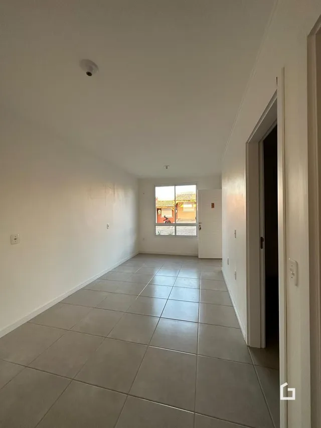 Vista de um corredor interno com piso de cerâmica claro.