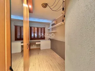 Sala de estar com piso de madeira clara e móveis brancos.