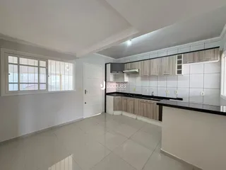 Ambiente de sala de estar e cozinha com piso de cerâmica claro e armários de madeira.