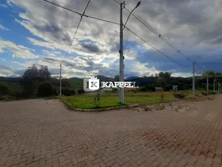 Vista panorâmica de uma área externa com gramado e colinas ao fundo.