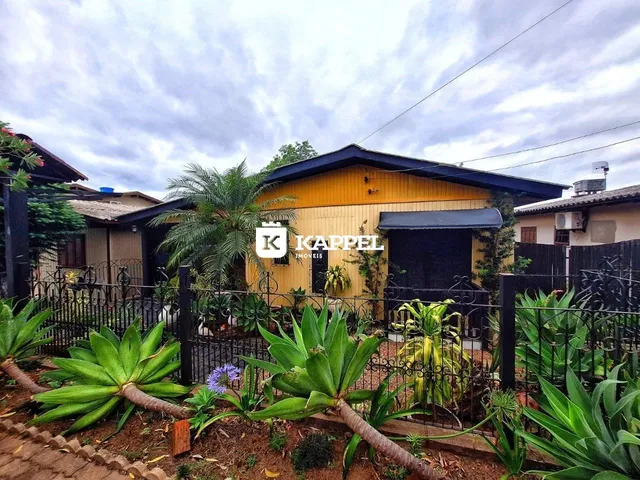 Fachada de uma casa amarela com cerca e vegetação em Lajeado, Brasil.