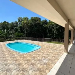 Foto de uma piscina externa com deck de pedra em um ambiente com vegetação.
