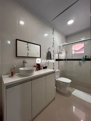 Banheiro com bancada branca e revestimento claro.