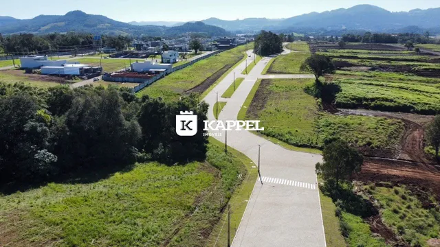 Vista aérea de uma paisagem rural com campos verdes e montanhas ao fundo.
