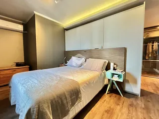 Quarto com cabeceira de madeira e armários em um apartamento no Brasil.