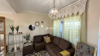 Sala de estar com sofá marrom e cortinas claras.