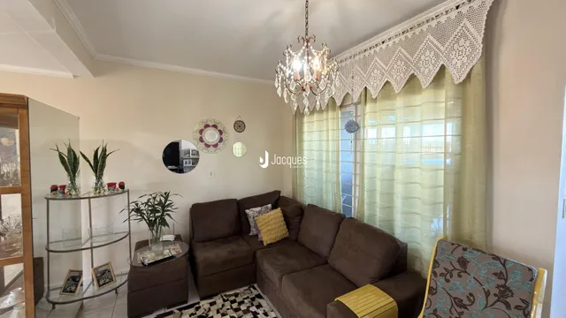 Sala de estar com sofá marrom e cortinas claras.
