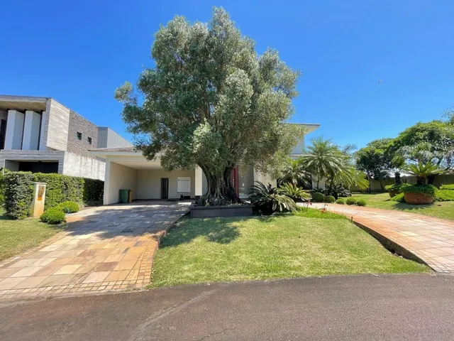 Fachada da residência com um grande árvore no jardim frontal.