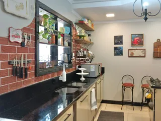Cozinha com bancada escura e revestimento de tijolo aparente.