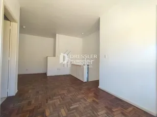 Interior de uma sala com piso de madeira e paredes brancas.