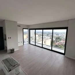 Foto de uma sala de estar com grandes janelas que dão vista para a cidade.