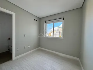 Foto de um cômodo interno com paredes cinzas e uma janela que mostra a vista externa.