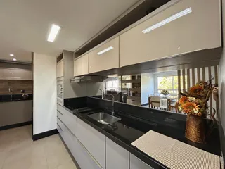 Cozinha moderna com armários brancos e bancadas escuras.