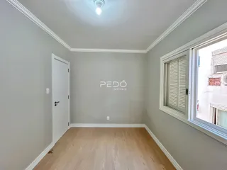 Uma sala com piso de madeira e paredes cinzas.