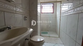Banheiro com pia e vaso sanitário em ambiente de cerâmica.
