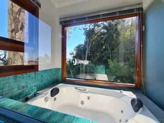 Banheira branca em um banheiro com revestimento de azulejos turquesa.