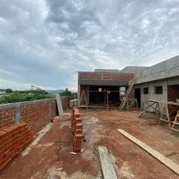 Vista externa de uma área com piso de terra e alvenaria visível.
