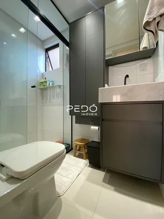 Foto interna de um banheiro moderno com revestimento branco.