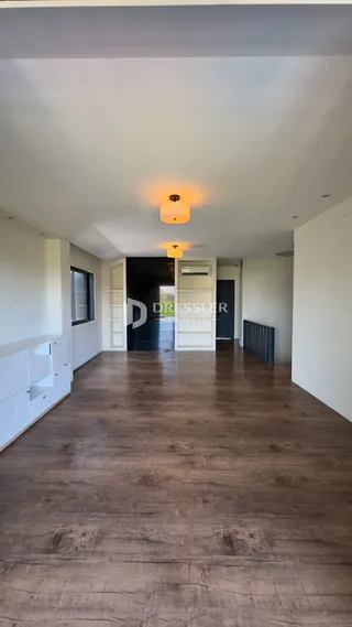 Corredor interno com piso de madeira e paredes brancas.