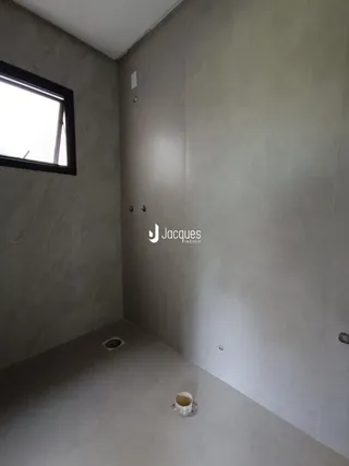 Vista interna de um ambiente com paredes de concreto e uma janela.