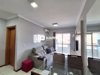 Sala de estar com sofá e televisão montada na parede.