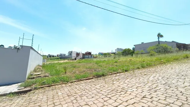 A foto mostra a fachada de uma propriedade com um muro branco e um terreno gramado.