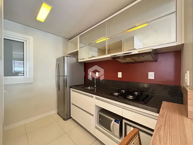 Foto de uma cozinha moderna com armários brancos e bancada escura.