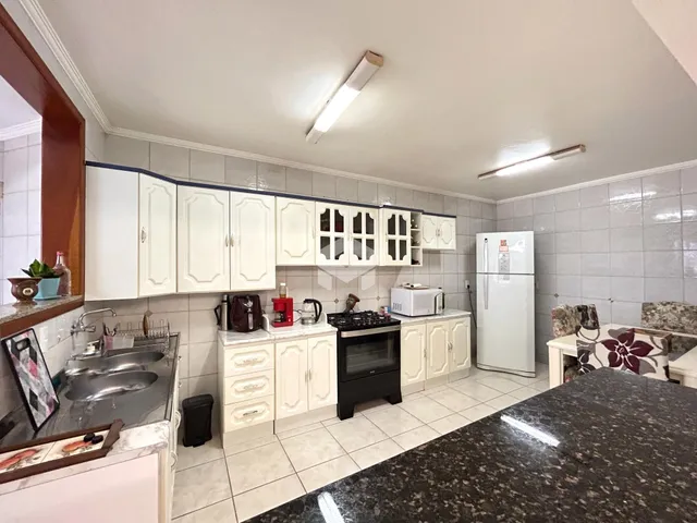 Foto de uma cozinha com armários brancos e piso de cerâmica.