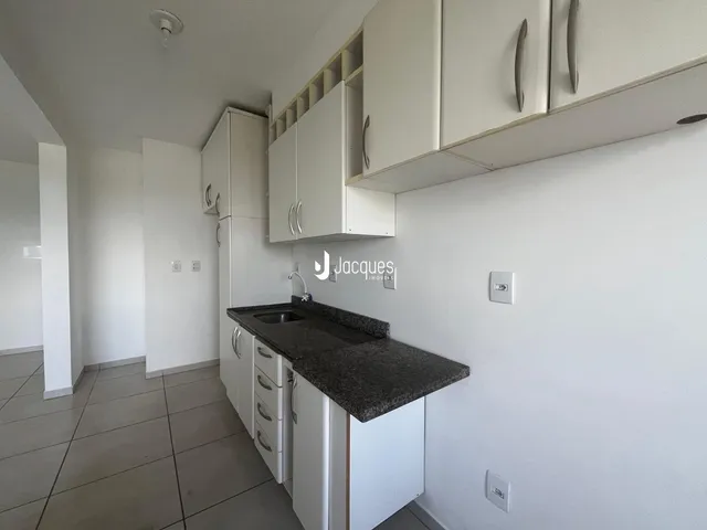 Uma cozinha moderna com armários brancos e bancadas escuras.