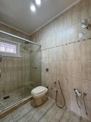 Foto interna de um banheiro com revestimento cerâmico e box de vidro.