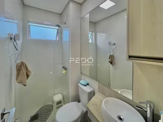 Interior de um banheiro com box de vidro e louças brancas.