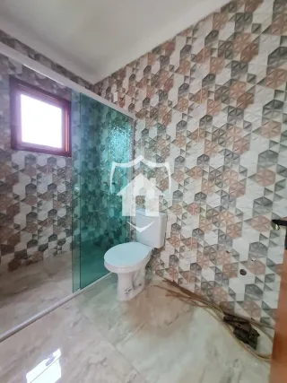 Foto de um banheiro com revestimento de azulejos e divisória de vidro.