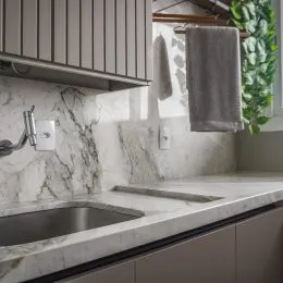 Foto de uma bancada de cozinha com pia e revestimento de mármore claro.