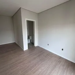 Sala de estar com piso de madeira clara e paredes brancas.