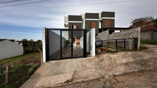 Fachada de uma residência em Lajeado, Brasil, com portão de vidro e muro.