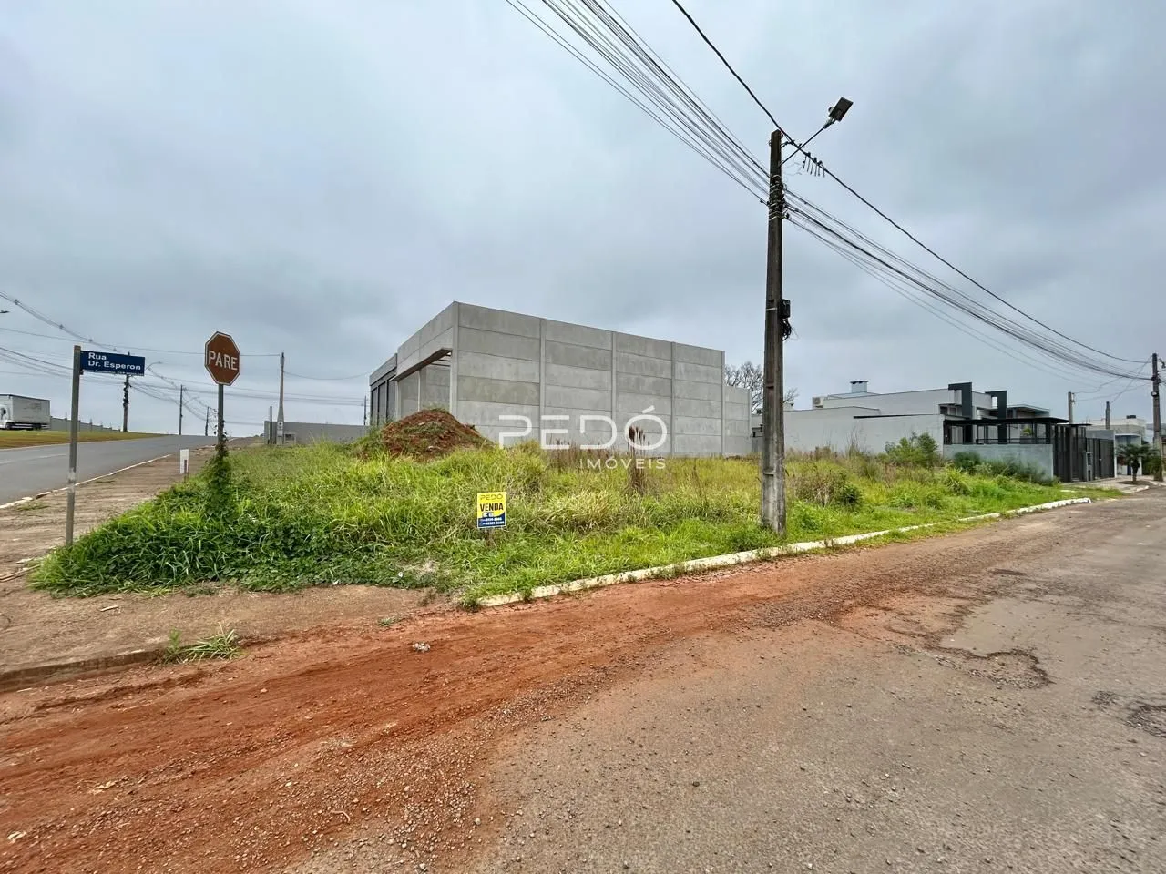 Vista externa de uma propriedade com terreno e vegetação ao redor.