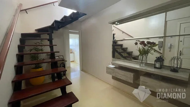 Hall de entrada com escadaria de madeira no interior da residência.
