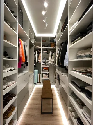 Corredor com estantes de armário preenchidas com roupas e sapatos.