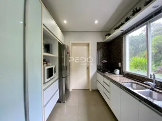 Vista interna de uma cozinha com armários brancos e bancadas de granito.