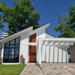 Fachada de uma residência branca com porta de vidro e área coberta.