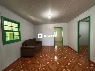 Sala de estar com sofá marrom e piso de madeira no imóvel em Lajeado.