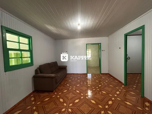 Sala de estar com sofá marrom e piso de madeira no imóvel em Lajeado.
