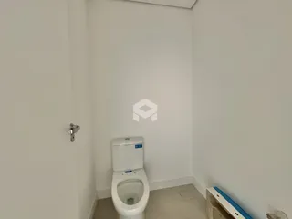 Vista de um banheiro com vaso sanitário branco e porta na parede
